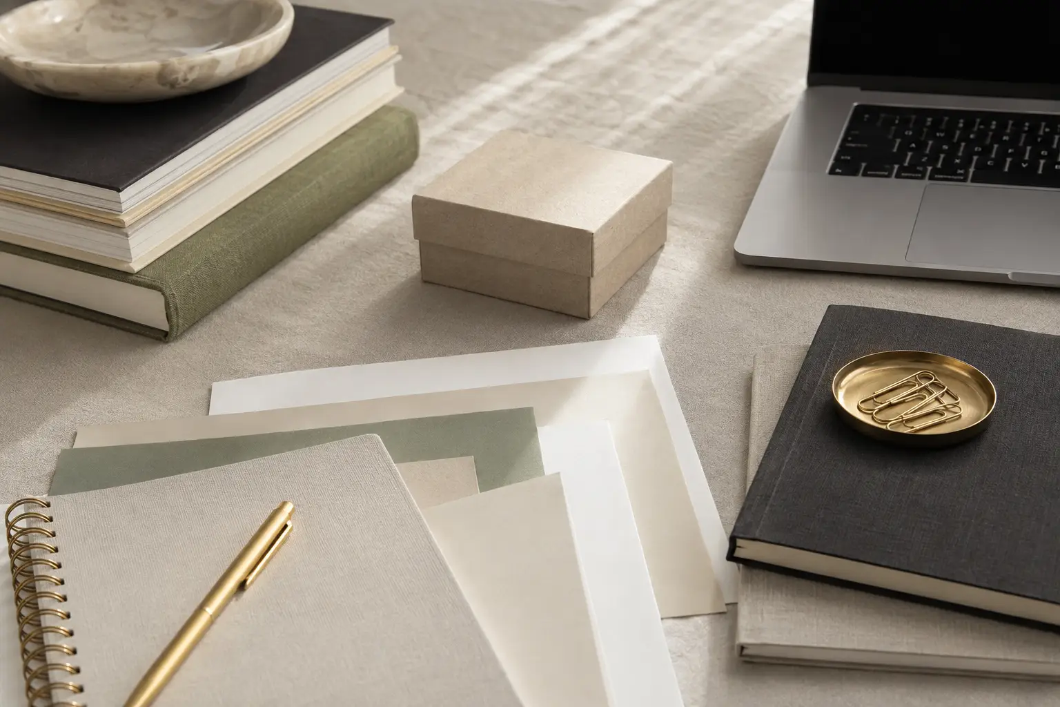 Books, notebook, laptop and neutral product materials arranged as owned business assets.