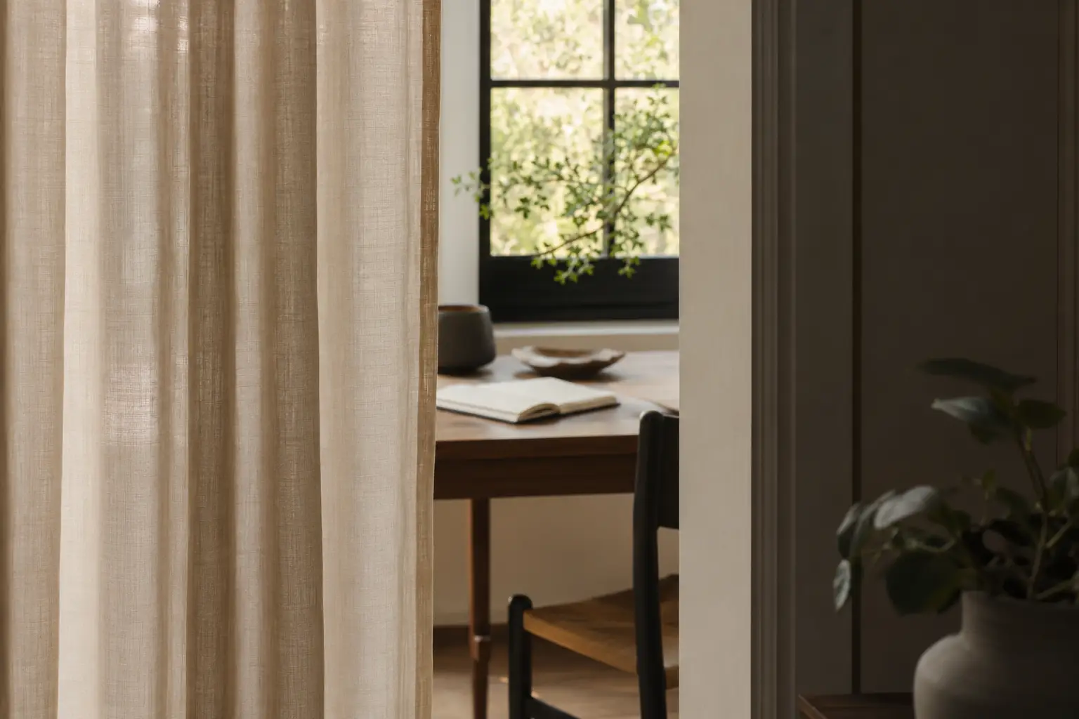 Partly closed linen curtain framing a quiet workspace, symbolizing intentional privacy boundaries.